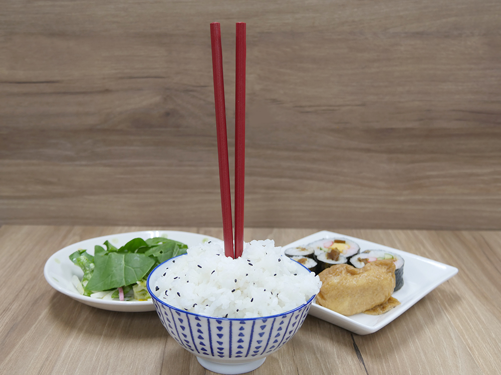 A vertical set of chopsticks on a rice bowl