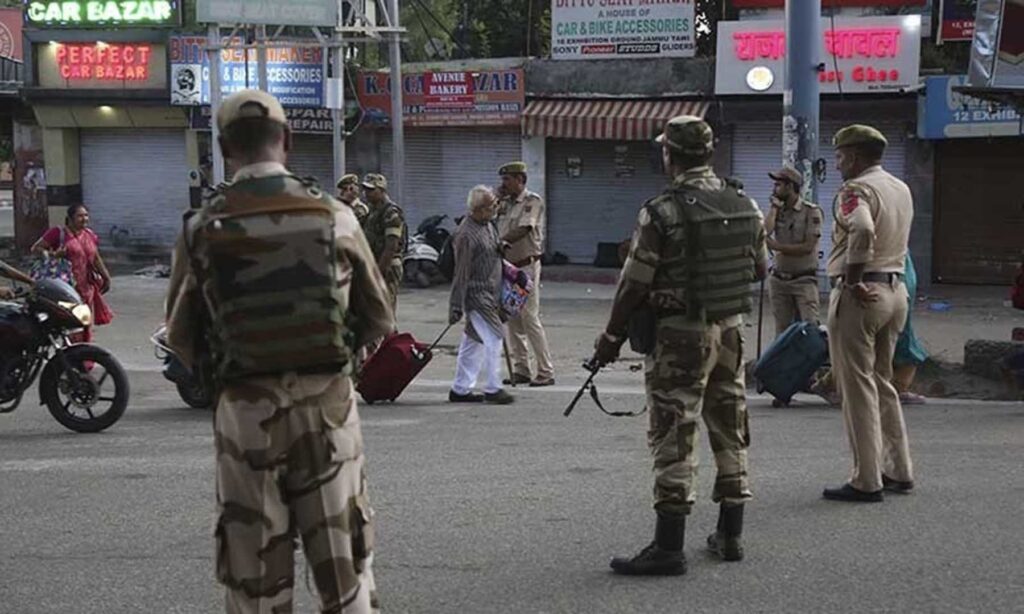 Tourists walk past Indian security forces during curfew like restrictions in Jammu, India, Monday, Aug. 5, 2019. 